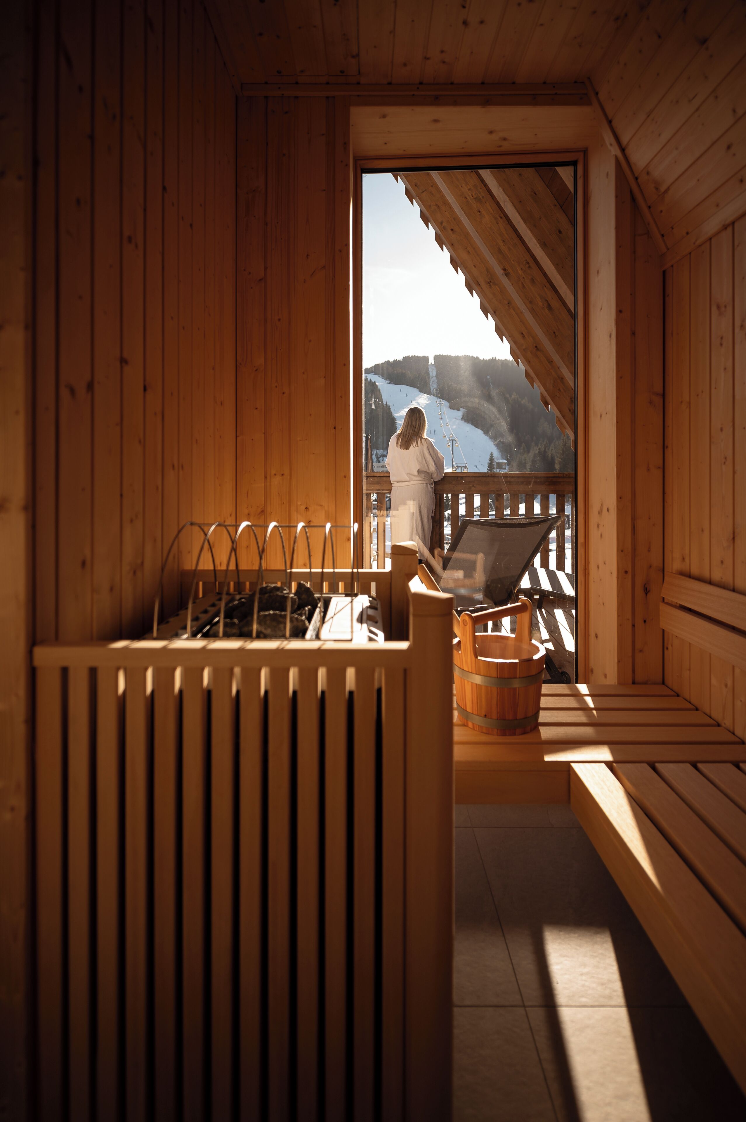 Une cabane en bois dotée d’un balcon, d’un banc en bois et d’une étagère en métal.