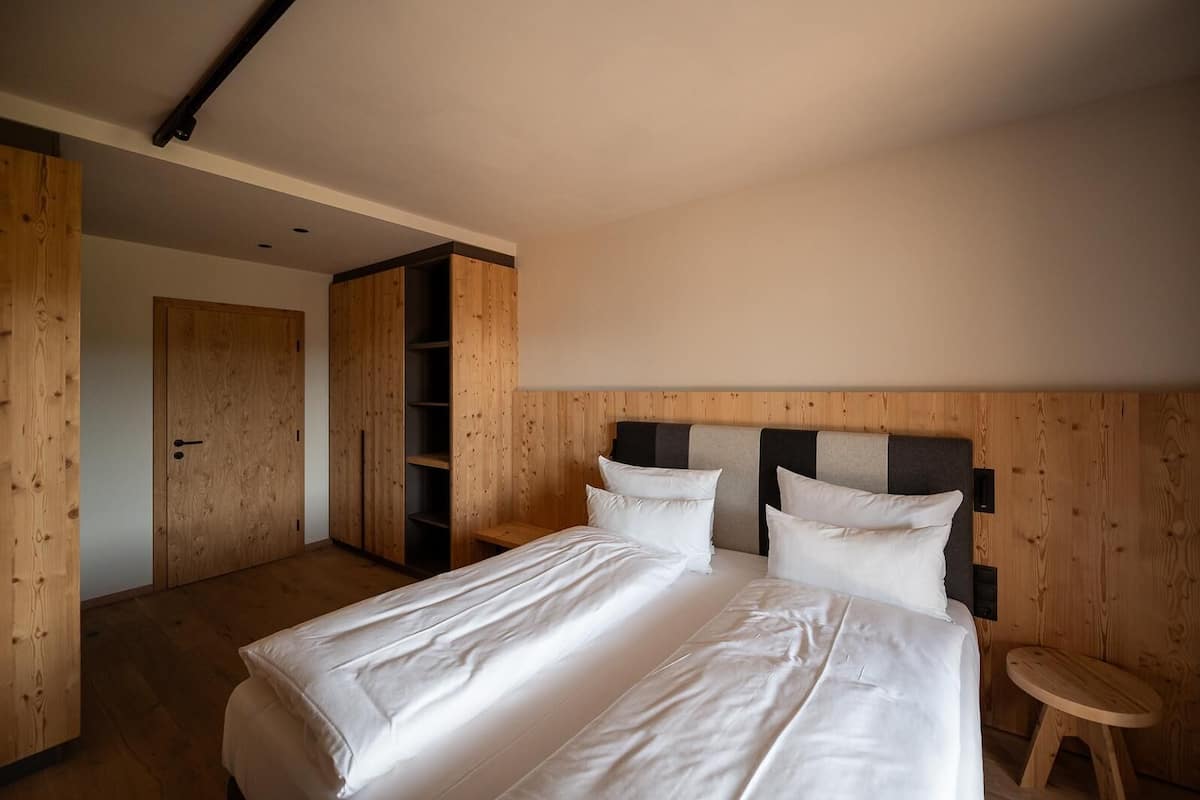 Un dormitorio con una cama grande, un armario de madera y un taburete pequeño.