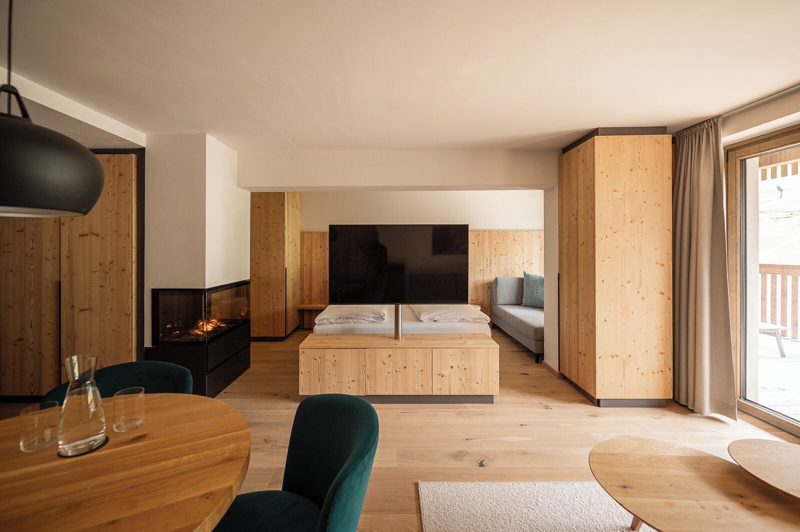 Une pièce moderne et bien éclairée, dotée d’un plancher en bois, d’une table à manger avec des chaises, d’un canapé, d’un téléviseur et d’une cheminée.