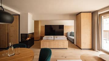 Una habitación moderna y bien iluminada con suelo de madera, una mesa de comedor con sillas, un sofá, un televisor y una chimenea.