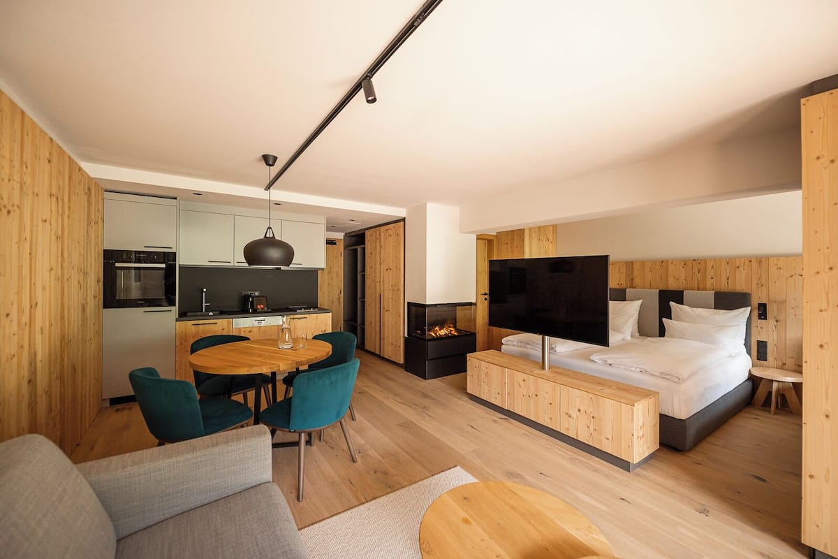 Un espacio habitable moderno y funcional, con kitchenette, comedor y dormitorio con televisor grande y cama confortable.