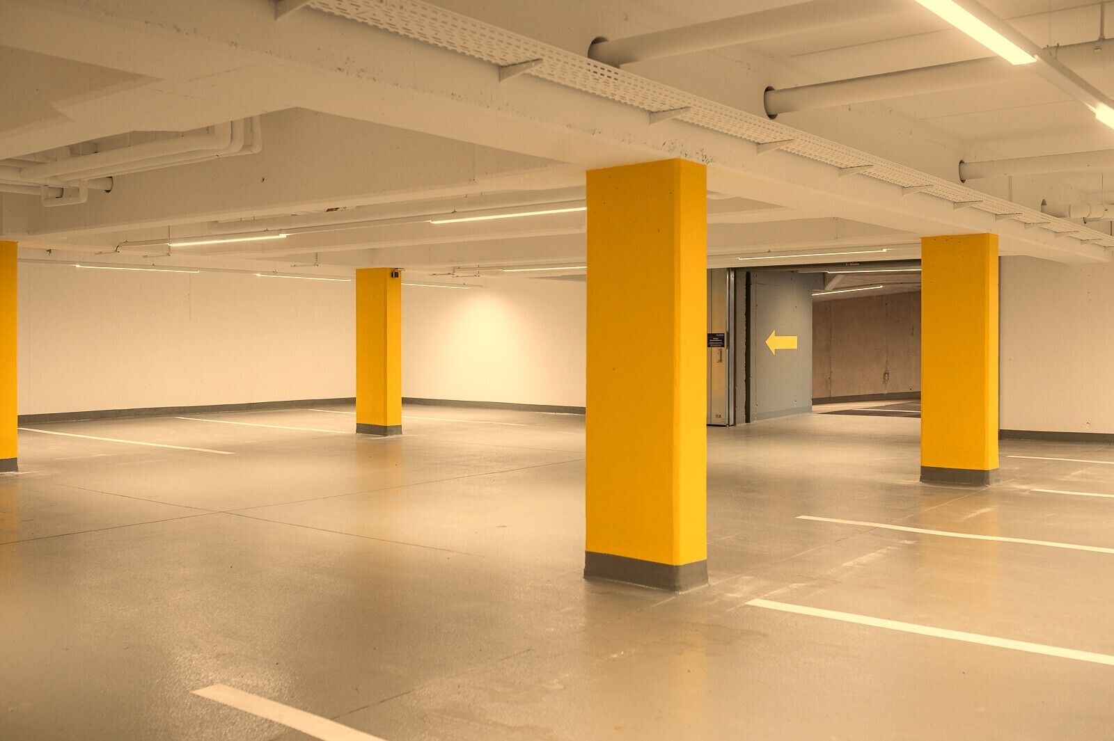 An empty parking garage with yellow pillars and white walls.