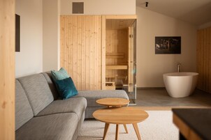Una sala de estar moderna con un sofá gris, cojines turquesa, una mesa de centro de madera, una bañera blanca y una pared de madera.