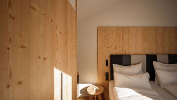 Un dormitorio con cabecera de madera, una mesita de noche redonda de madera y una cama con ropa blanca.