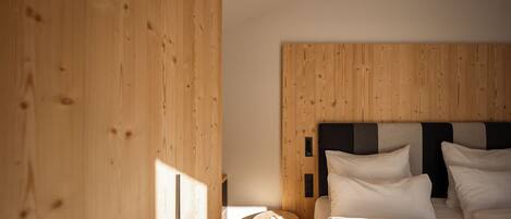 A bedroom with a wooden headboard, a round wooden side table, and a bed with white bedding.