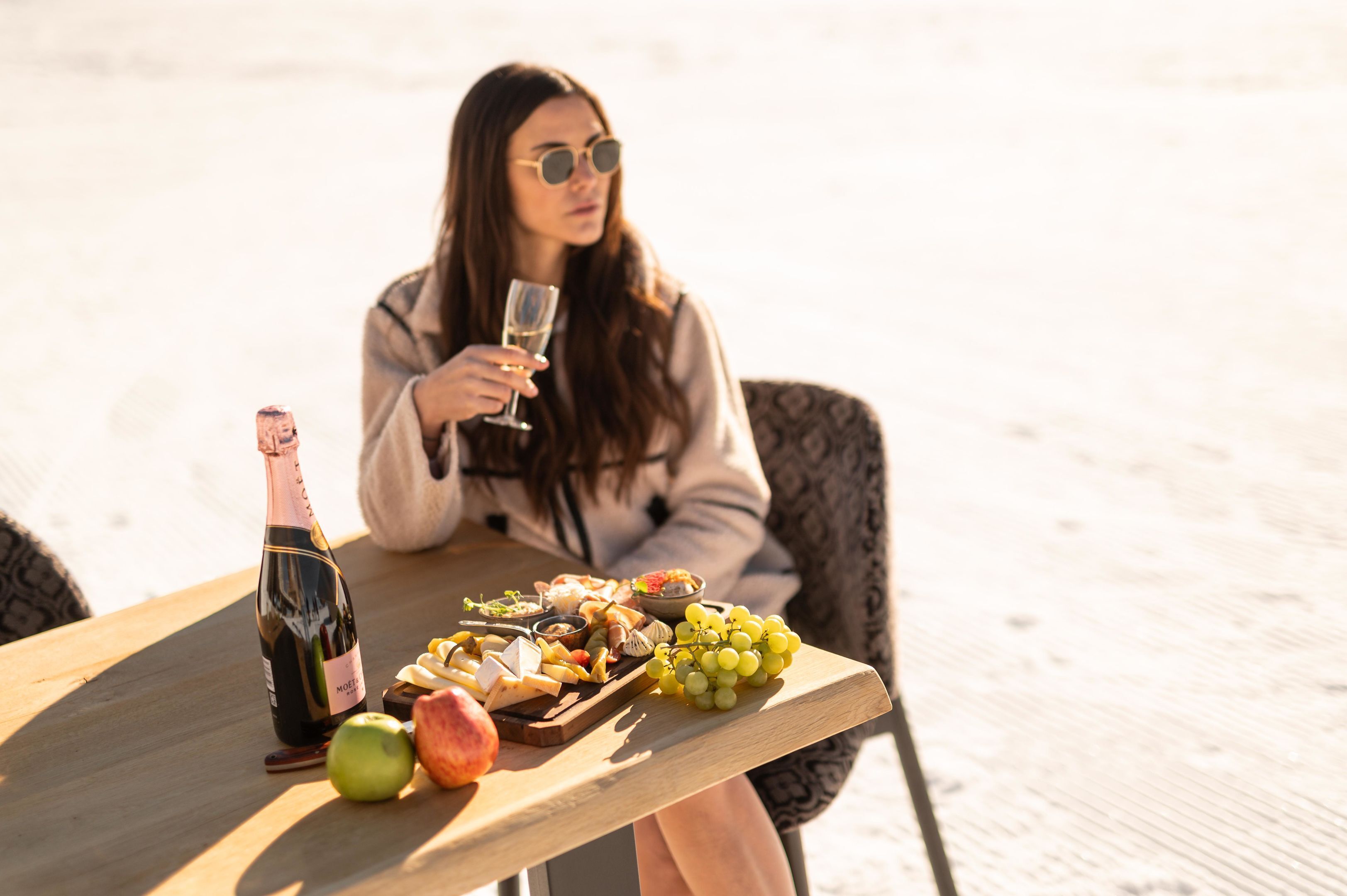 Une table avec une bouteille de vin, un saladier de fruits et un verre de vin.