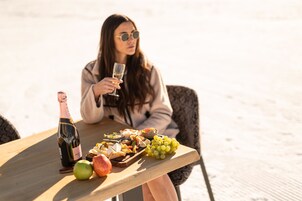 Una mesa con una botella de vino, un cuenco de fruta y una copa de vino.