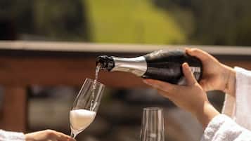 Dos personas sirviendo champán en copas de vino en una mesa con vistas a las colinas.