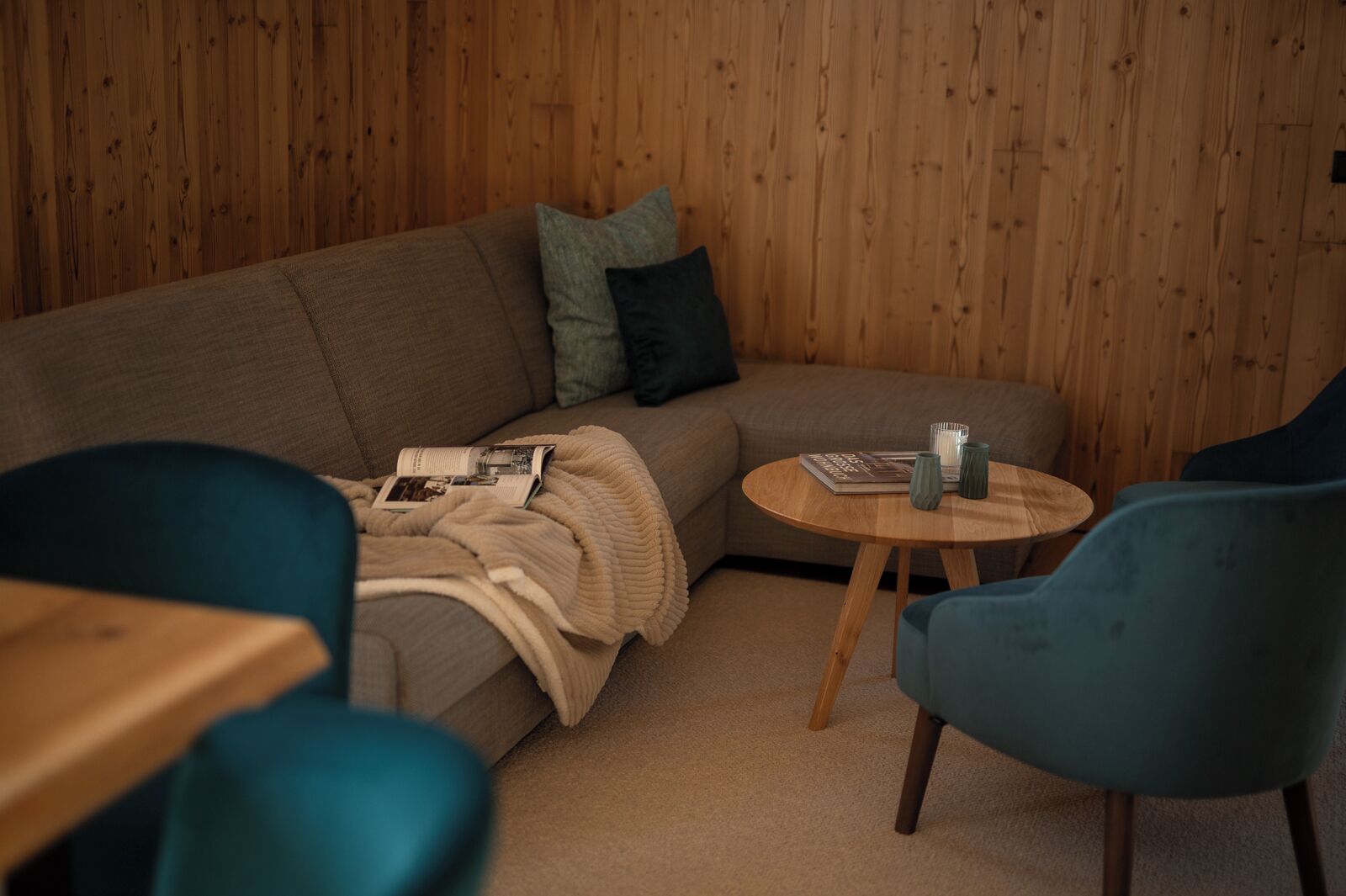 A cozy living room with a sofa, a round wooden coffee table, and two chairs.