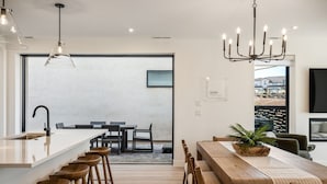A modern kitchen with a central island, bar stools, and a dining area with a wooden table and chairs. - The Beach Club 5 Bedroom Home (St. George)