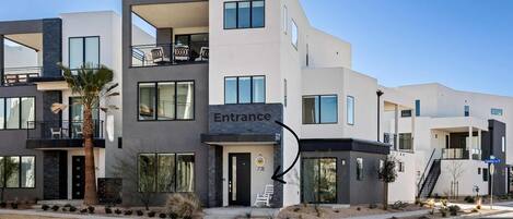 A modern multi-story building with an entrance marked by a sign.