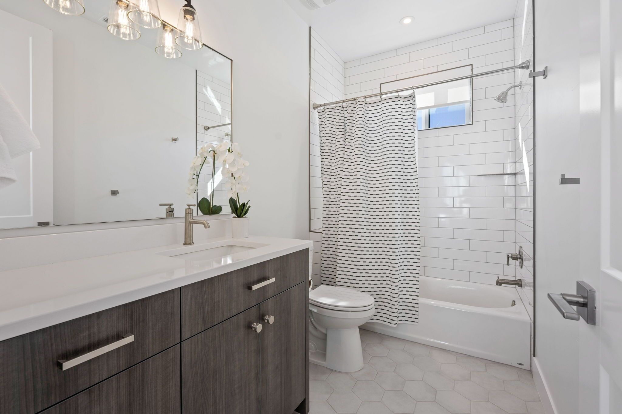 A modern bathroom with a white sink, dark wooden cabinets, a white toilet, and a white bathtub.