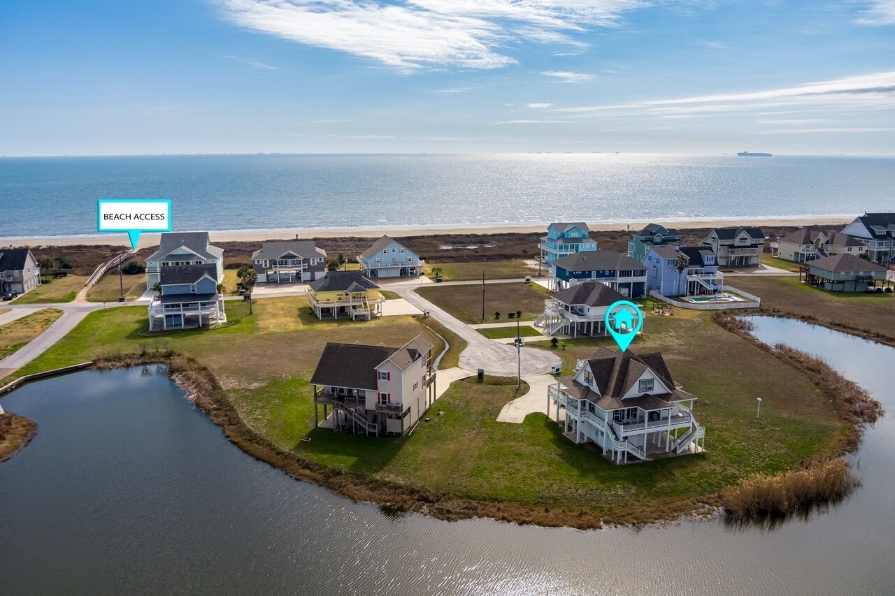 A coastal residential area with houses, a beach access point, and a small body of water.