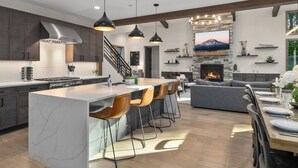Une cuisine moderne dotée d’un grand îlot central, de meubles de cuisine en bois foncé et d’une cheminée en pierre.