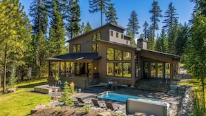 Une maison moderne à deux étages, dotée d’une grande terrasse, d’une piscine et d’un patio en pierre.