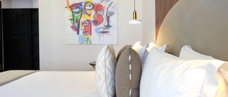 Un dormitorio moderno con una cama grande, un cuadro abstracto y colorido en la pared, y un panel de madera a la derecha.