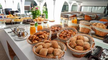 Un bufé con panes, pasteles y bebidas variados.