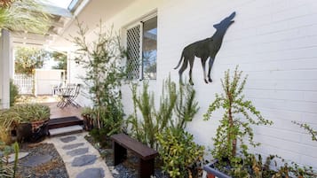 Enjoy a serene outdoor space with a unique dog silhouette, lush greenery, and a cozy bench along a stone pathway.