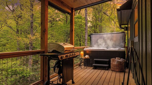 A wooden deck with a grill, a hot tub, and a basket of towels. - In Boone! Hot Tub - Firepit - Sleeps 10 - Wifi (Boone)