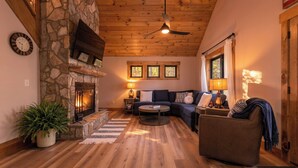 A cozy living room with a stone fireplace, wooden ceiling, and a sofa set. - In Boone! Hot Tub - Firepit - Sleeps 10 - Wifi (Boone)