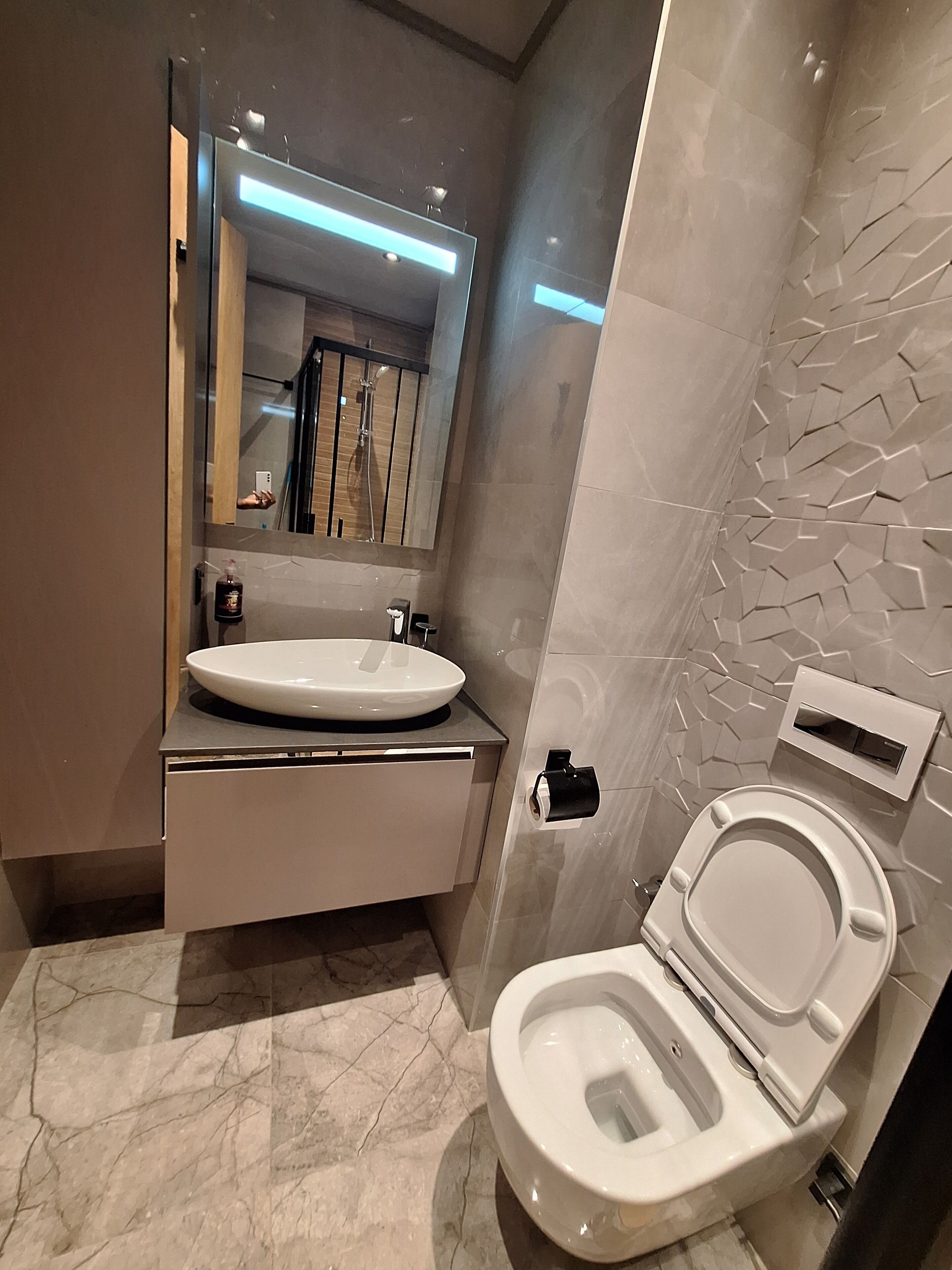A modern bathroom with a white sink, a toilet, and a mirror.