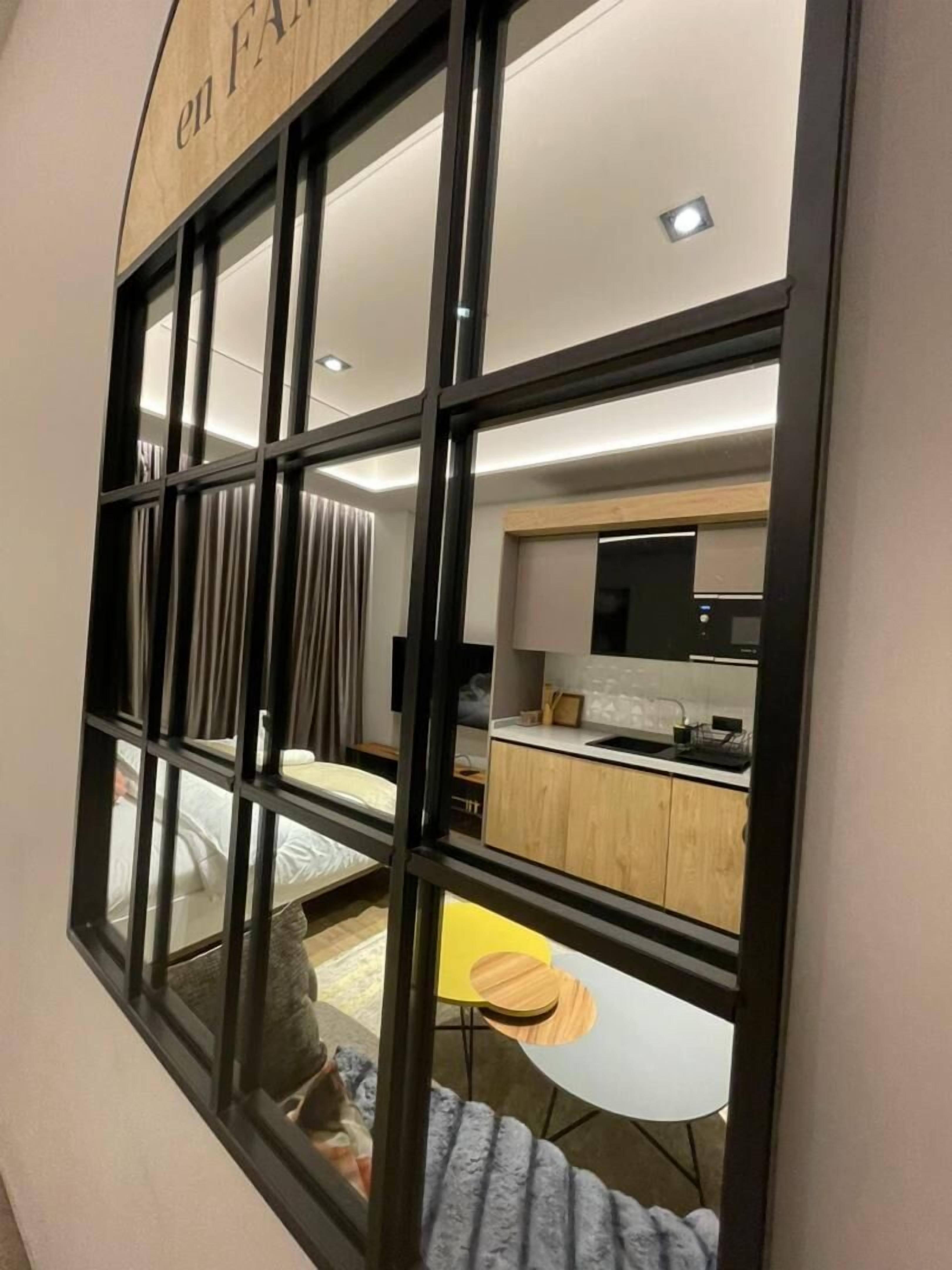 Ein modernes Interieur mit einer Küche, einem Essbereich und einem Bett, das durch ein Fenster zu sehen ist.