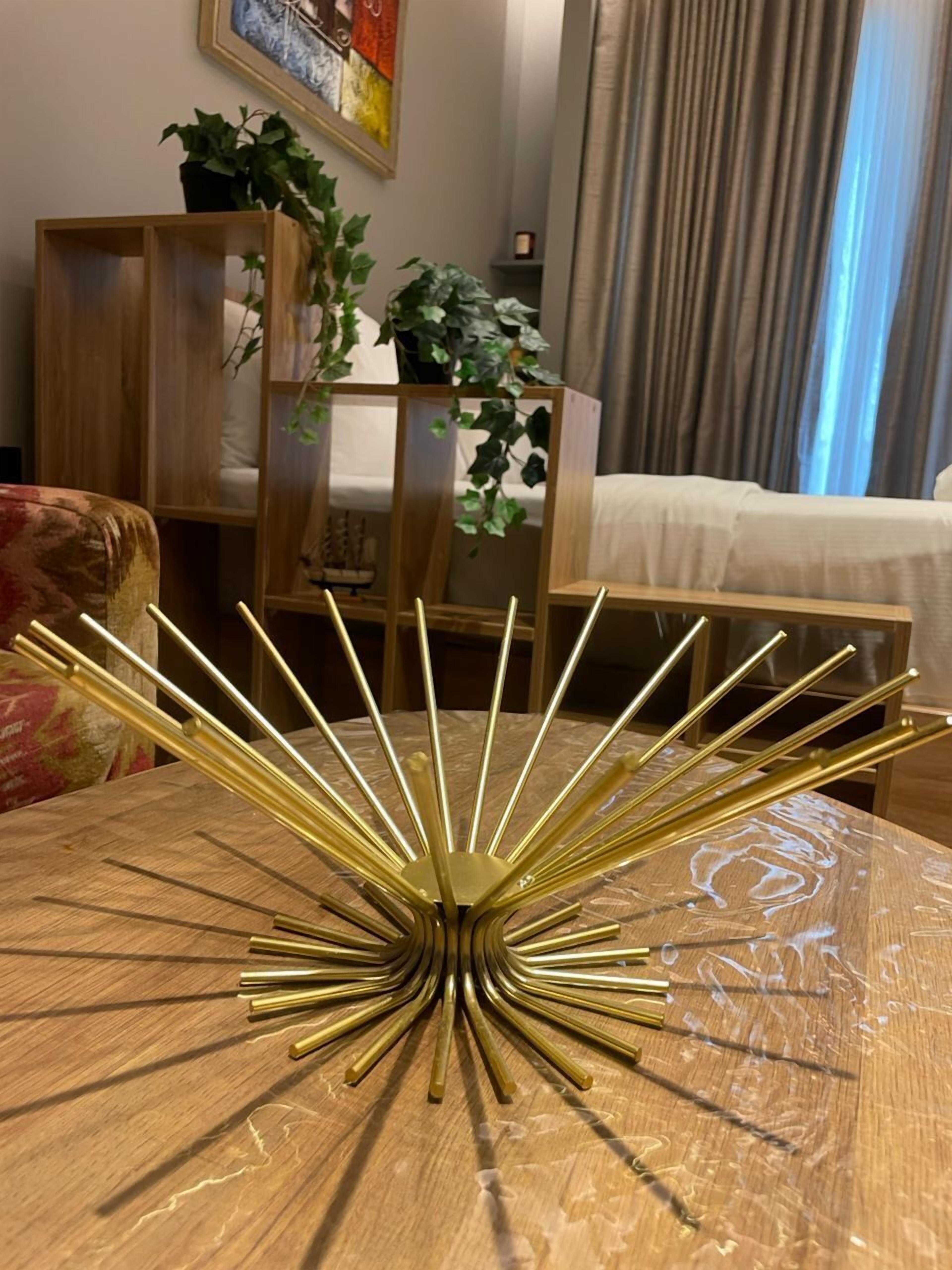 Une pièce avec une table ronde en bois, un objet décoratif doré placé au centre, un canapé, un lit et un tableau accroché au mur.