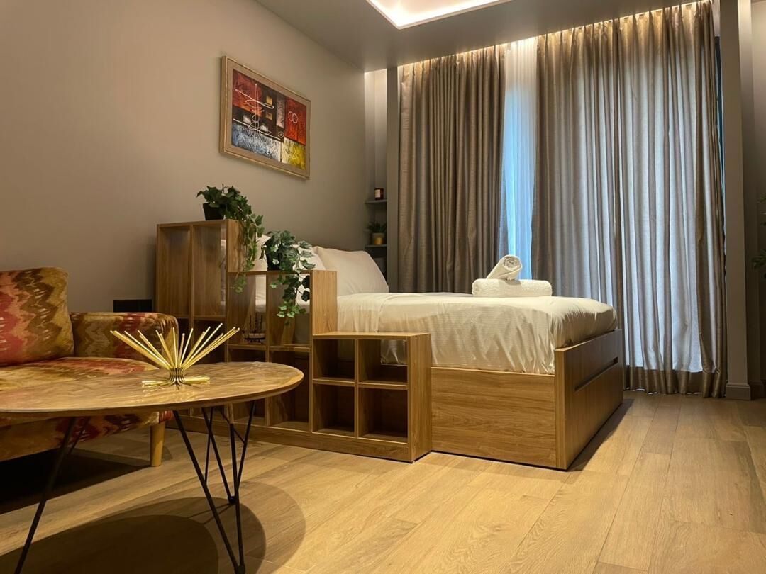 A modern bedroom with a bed, a wooden nightstand, a round table, and a sofa.