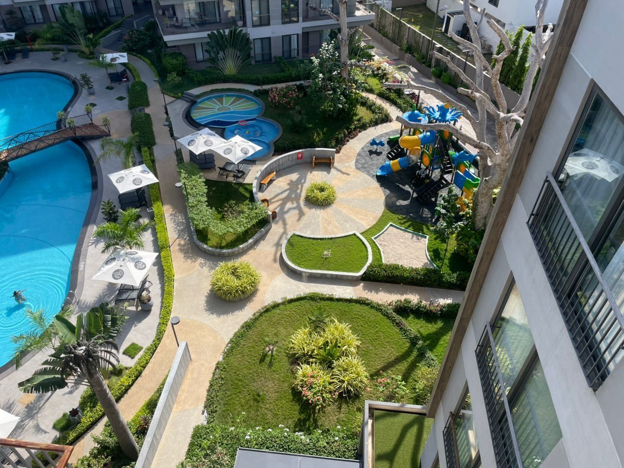 Un área de piscina en la azotea con varias piscinas, tumbonas y una zona de juegos para niños.