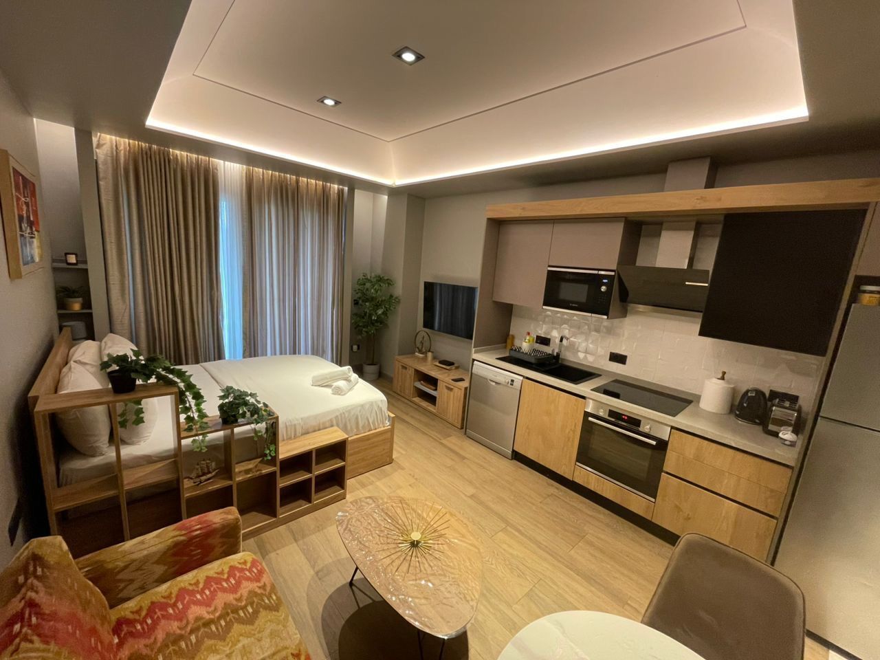Ein kompaktes Hotelzimmer mit Bett, Küchenzeile und einer kleinen Essecke.