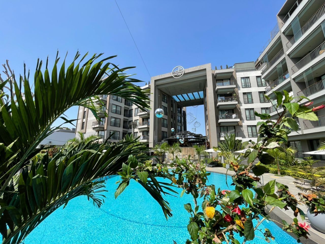 A hotel with a swimming pool, modern architecture, and a clear sky.