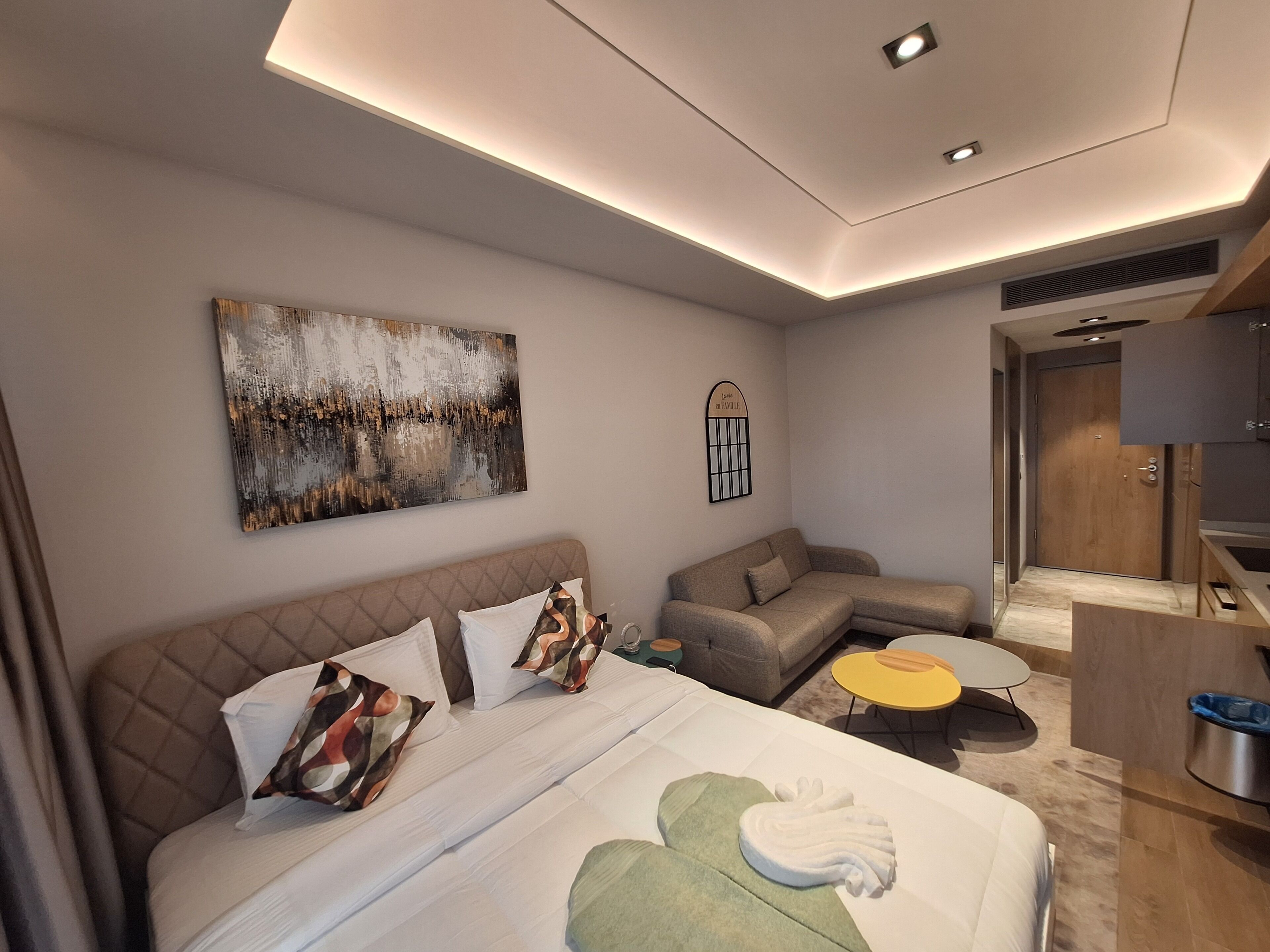 Et moderne hotelværelse med en stor seng, en sofa, et lille bord og et fjernsyn.