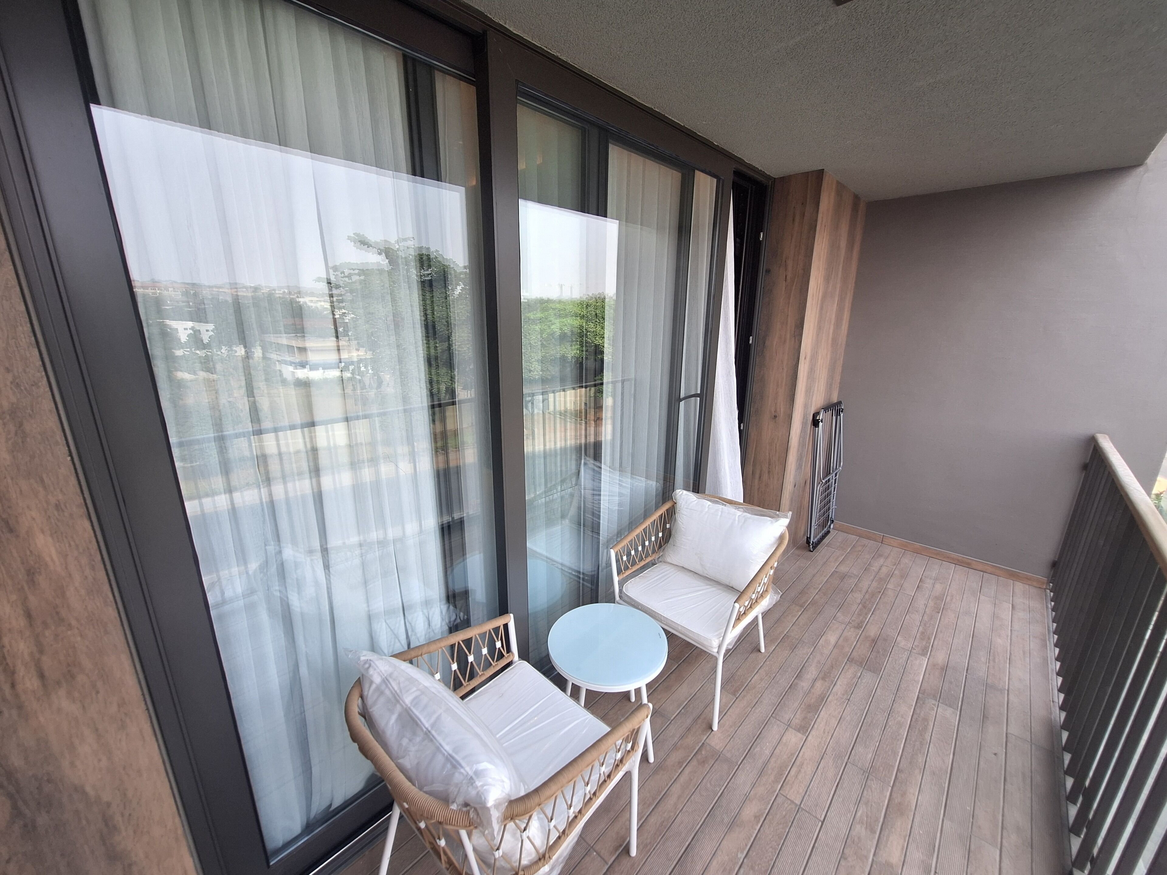 A balcony with wicker furniture, a small round table, and a radiator.