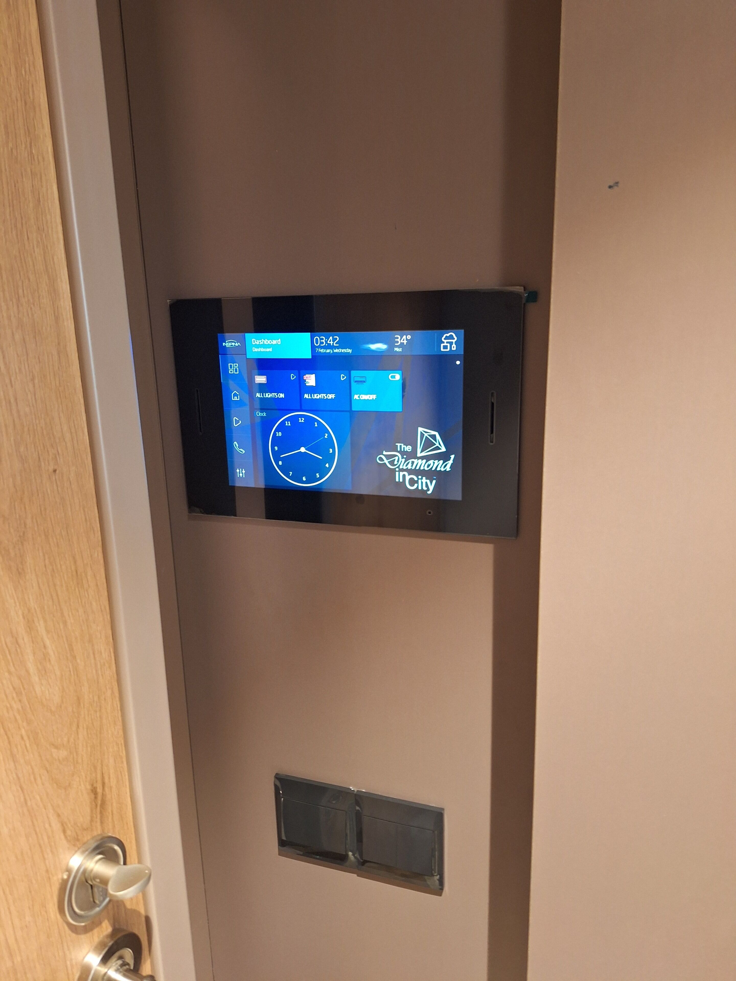 A digital control panel on a door with a clock and a weather display.