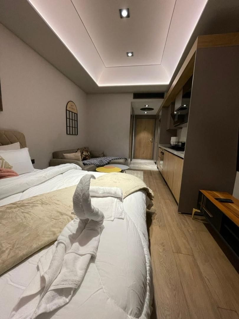 Un dormitorio moderno con dos camas, una pequeña sala de estar y una kitchenette.