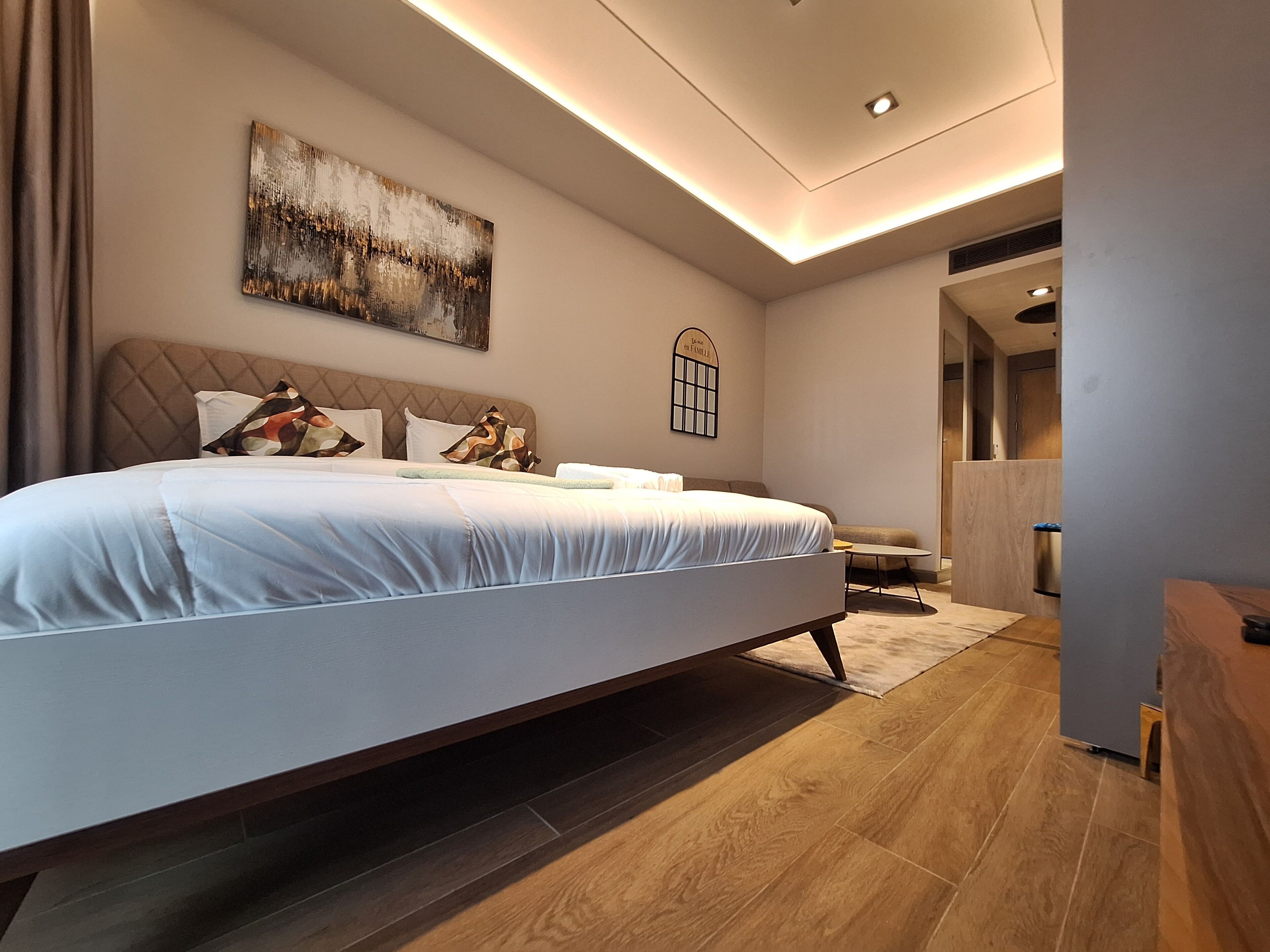 Ein modernes Schlafzimmer mit einem großen Bett, einem Nachttisch, einer Wandlampe und einem Wandbild.