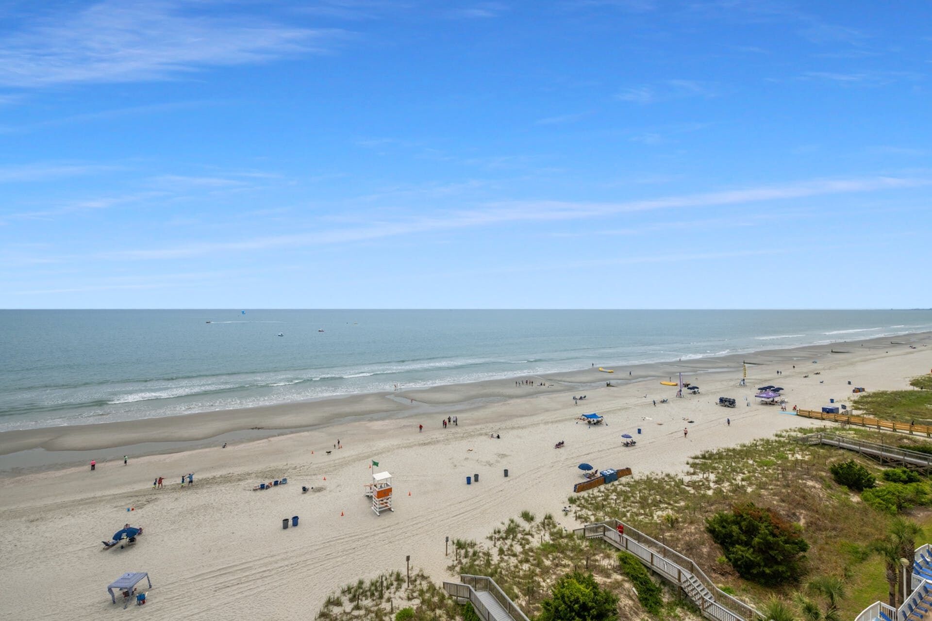 Une plage avec un poste de surveillance pour les sauveteurs, des parasols et une promenade en bord de mer.