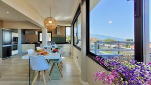 A modern kitchen with a dining area, large windows, and a view of the city. - Villa with Privacy and Spectacular Views of Teide, Sea, Orotava Valley (La Orotava)