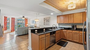 A modern kitchen with wooden cabinets, a central island, and a built-in dishwasher.
