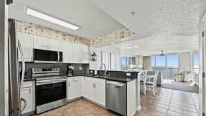 A modern kitchen with white cabinets, stainless steel appliances, and a large island. - Luxurious 3-bedroom, 3-bathroom oceanfront condo, 7th floor views | Windy Hill Dunes - 703 (North Myrtle Beach)