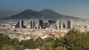 A cityscape with a prominent mountain in the background, modern high-rise buildings, and a mix of older architecture. - Panoramic apartment with large roof terrace in Naples, view of harbor, Vesuvius (Neapel)