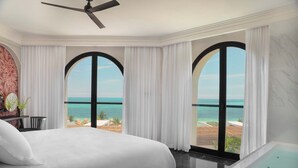 A hotel room with a large bed, a bathtub, and a view of the ocean through arched windows. - Excellence Coral Playa Mujeres - Adults Only All Inclusive (Punta Sam)