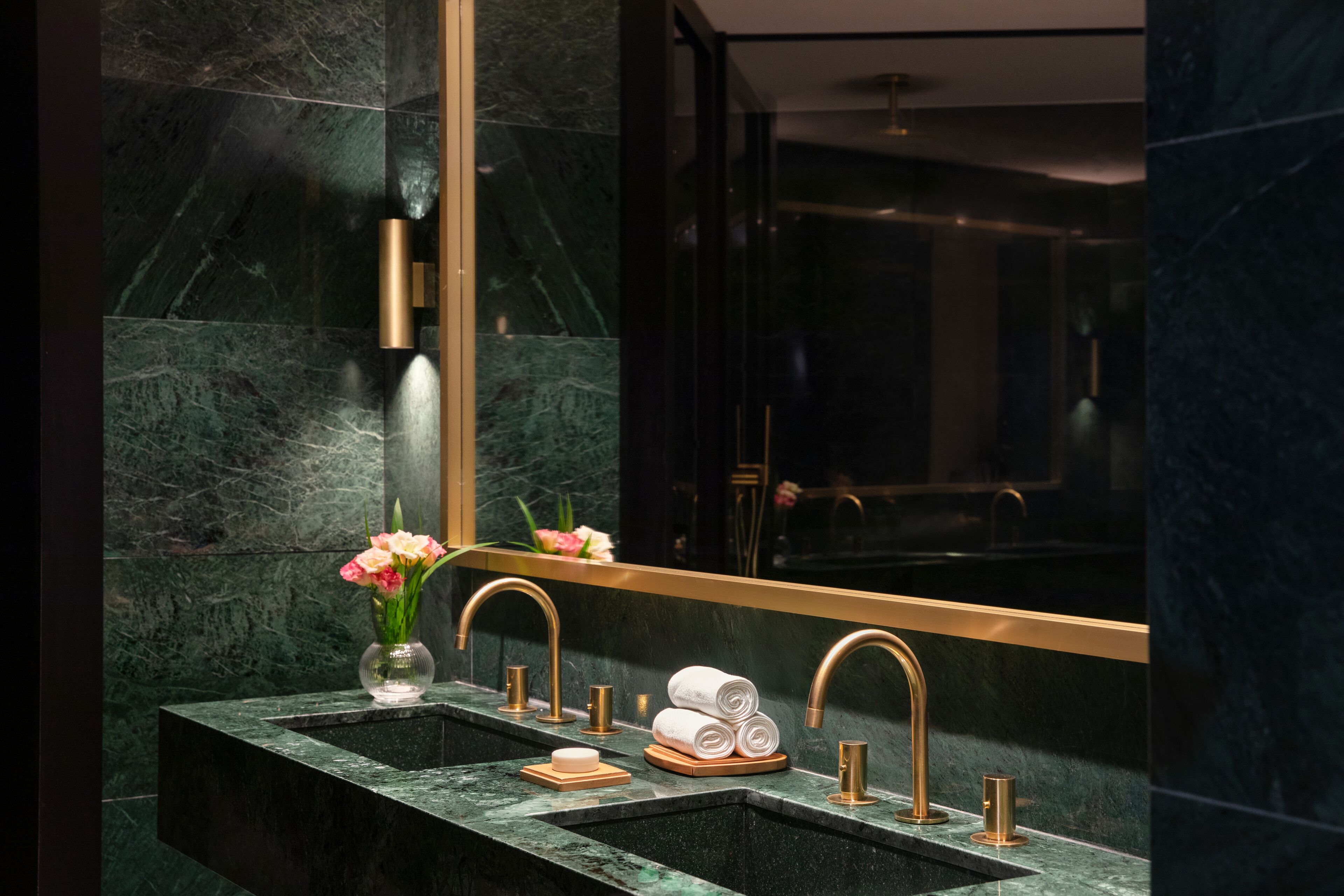 Une salle de bain moderne avec un double vasque, des murs en marbre et un grand miroir.