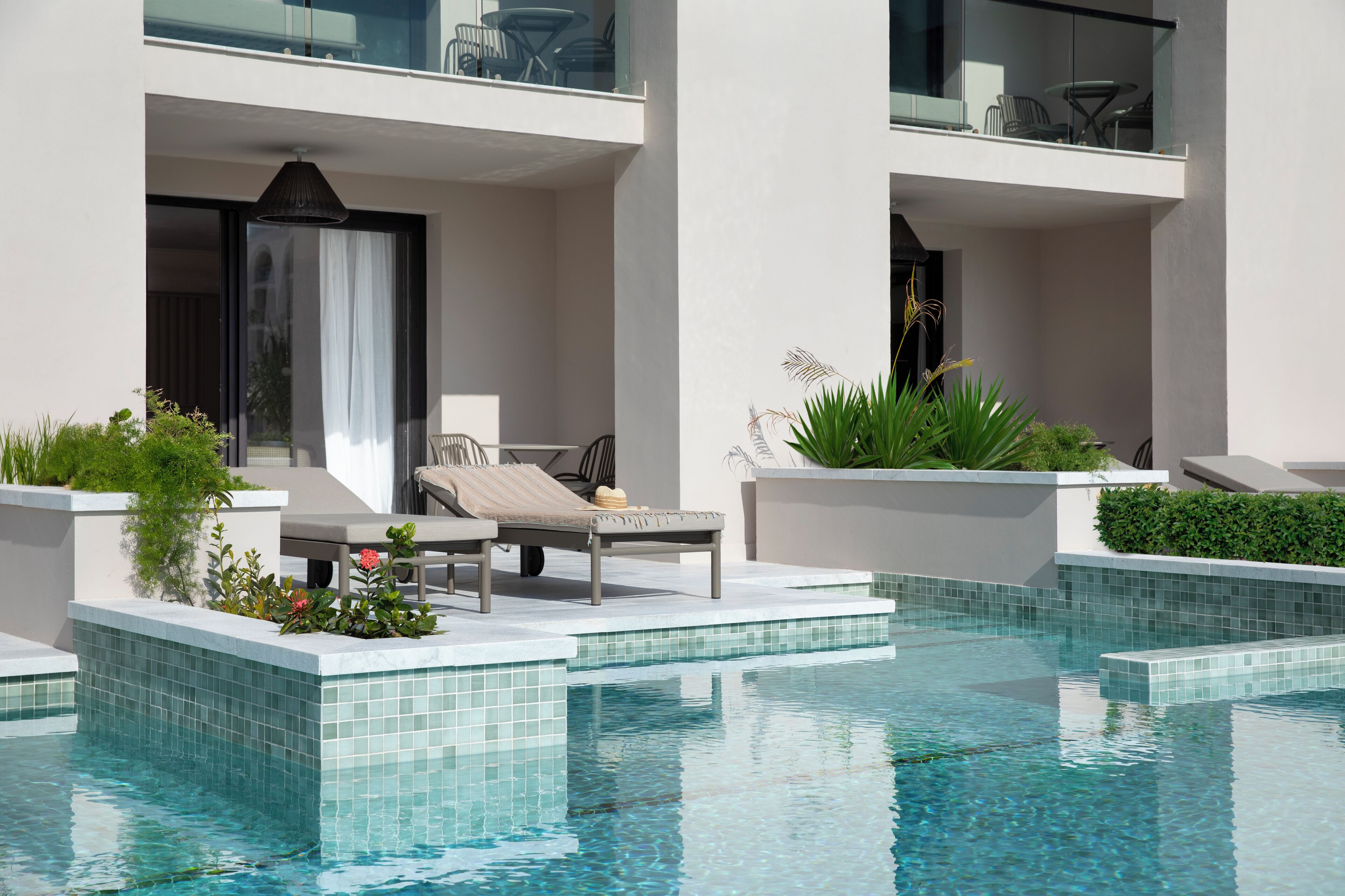 Un área de piscina moderna con sillones de descanso y balaustrada de vidrio.