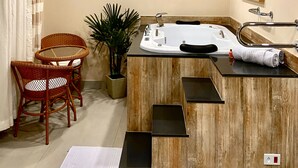 Une salle de bain moderne avec une baignoire, un lavabo et une douche. On y trouve une plante en pot et une chaise en osier.