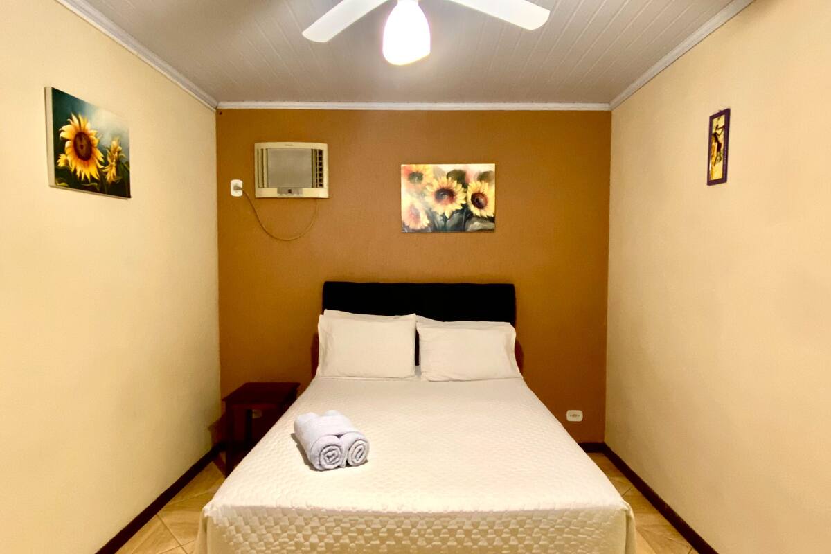 Ein Hotelzimmer mit einem Bett, einem Deckenventilator und Kunstwerken an den Wänden.