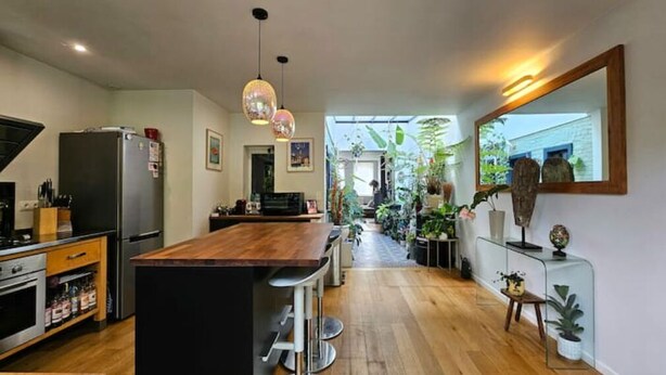 Una cocina moderna con una isla de madera, electrodomésticos de acero inoxidable y una vitrina de vidrio.