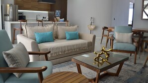 A modern living room with a sofa, chairs, a coffee table, and a kitchen in the background. - Amazing views coastal apartment. 2BD (Puerto Vallarta)