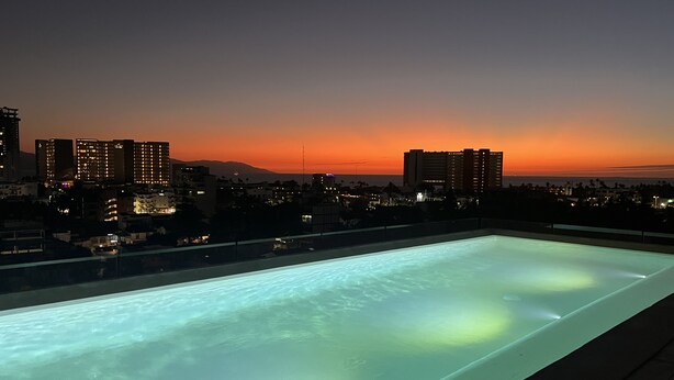 A rooftop pool with a cityscape view at dusk. - Amazing views coastal apartment. 2BD (Puerto Vallarta)