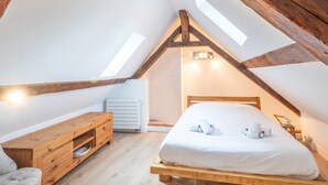 A cozy attic bedroom with a wooden bed, a wooden dresser, and a radiator.